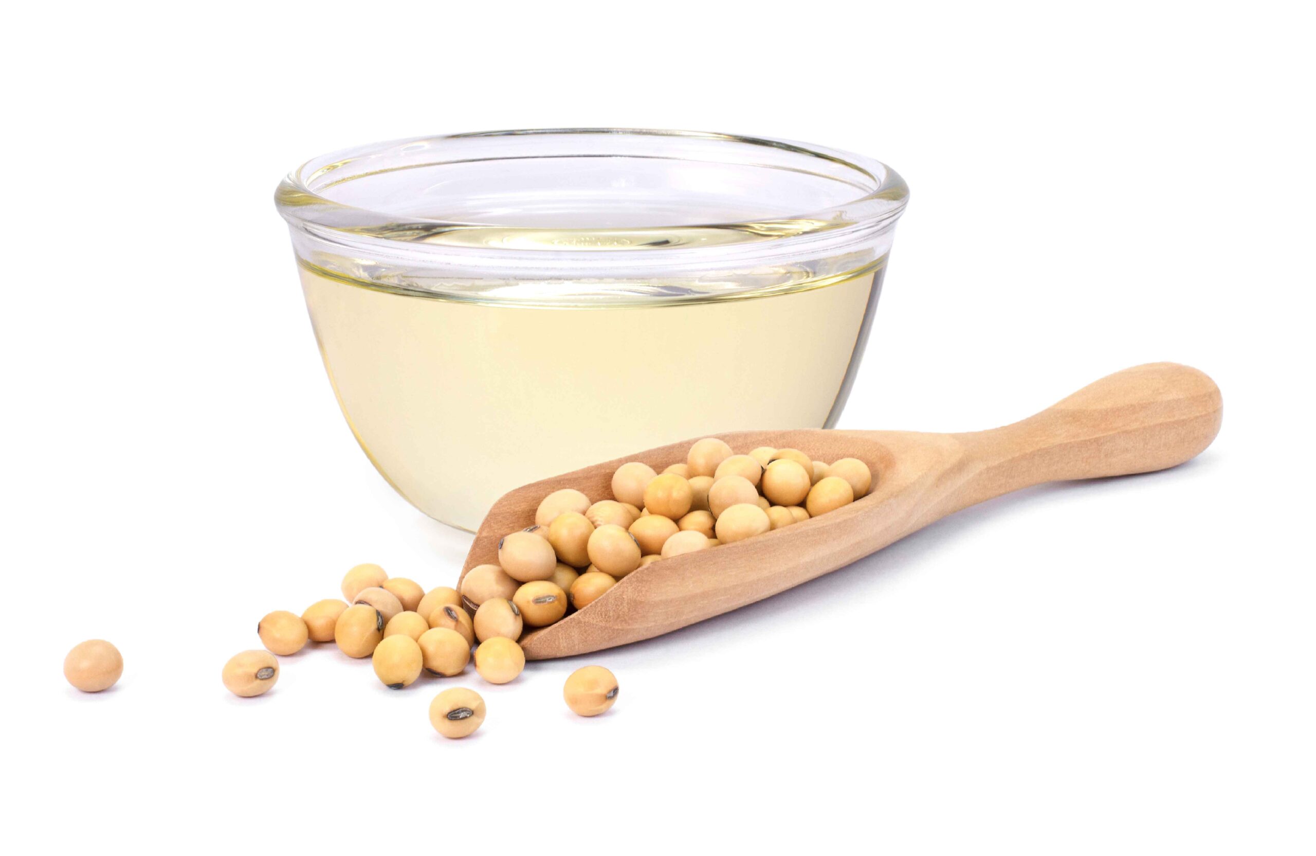 A glass bowl of soybean oil with a wooden scoop of soybeans on a white background.